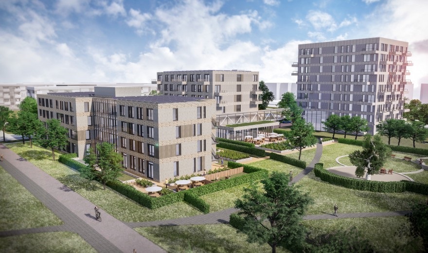 Luchtfoto van een modern wooncomplex met meerdere gebouwen, omgeven door groen en wandelpaden onder een blauwe lucht.