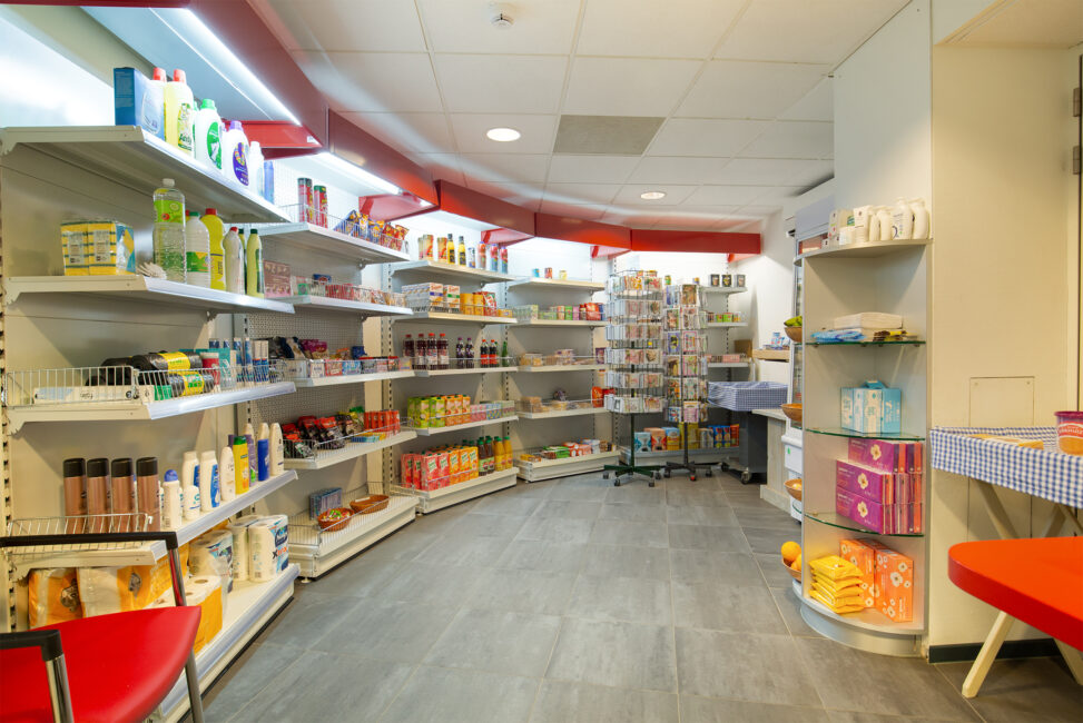 Een goed gevulde winkel met schappen vol diverse producten, waaronder schoonmaakmiddelen en voedingsmiddelen, in een lichte ruimte.