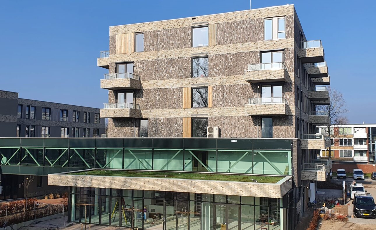 Nieuwbouw appartementencomplex Bloesemhove met moderne architectuur, grote ramen en balkons, onder een heldere blauwe lucht.