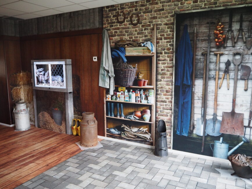Een rustieke kamer met houten en bakstenen muren, een plank met gereedschap en blikken, en een tv boven een open haard.
