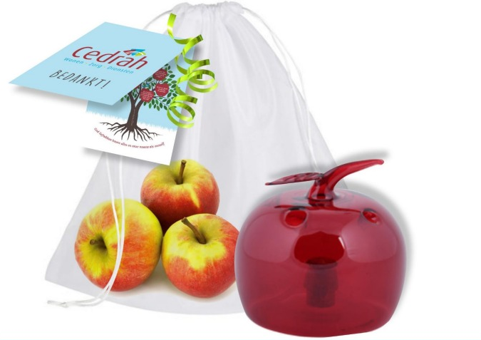 Afbeelding van een witte zak met drie appels en een rode appelvormige container, met een Cedrah-label eraan bevestigd.