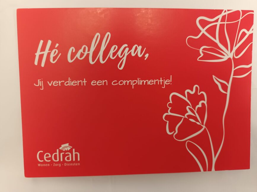 Rood kaartje met witte tekst: "Hé collega, Jij verdient een complimentje!" en een tekening van bloemen. Cedrah-logo onderaan.