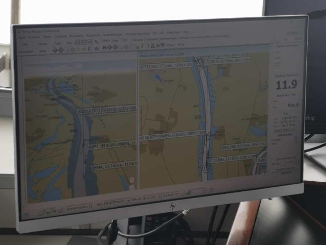 Een computerscherm toont een navigatiekaart met een rivier en omliggende gebieden. Rechts staat een getal: 11.9.