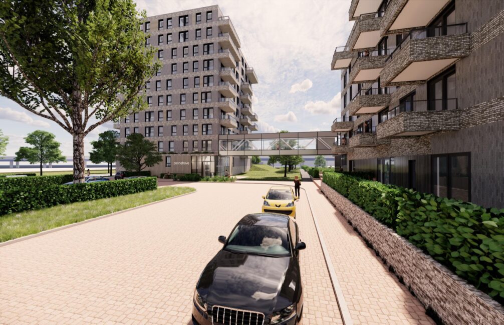 Straatbeeld met moderne appartementen, geparkeerde auto's en een loopbrug tussen gebouwen. Bomen en blauwe lucht op de achtergrond.
