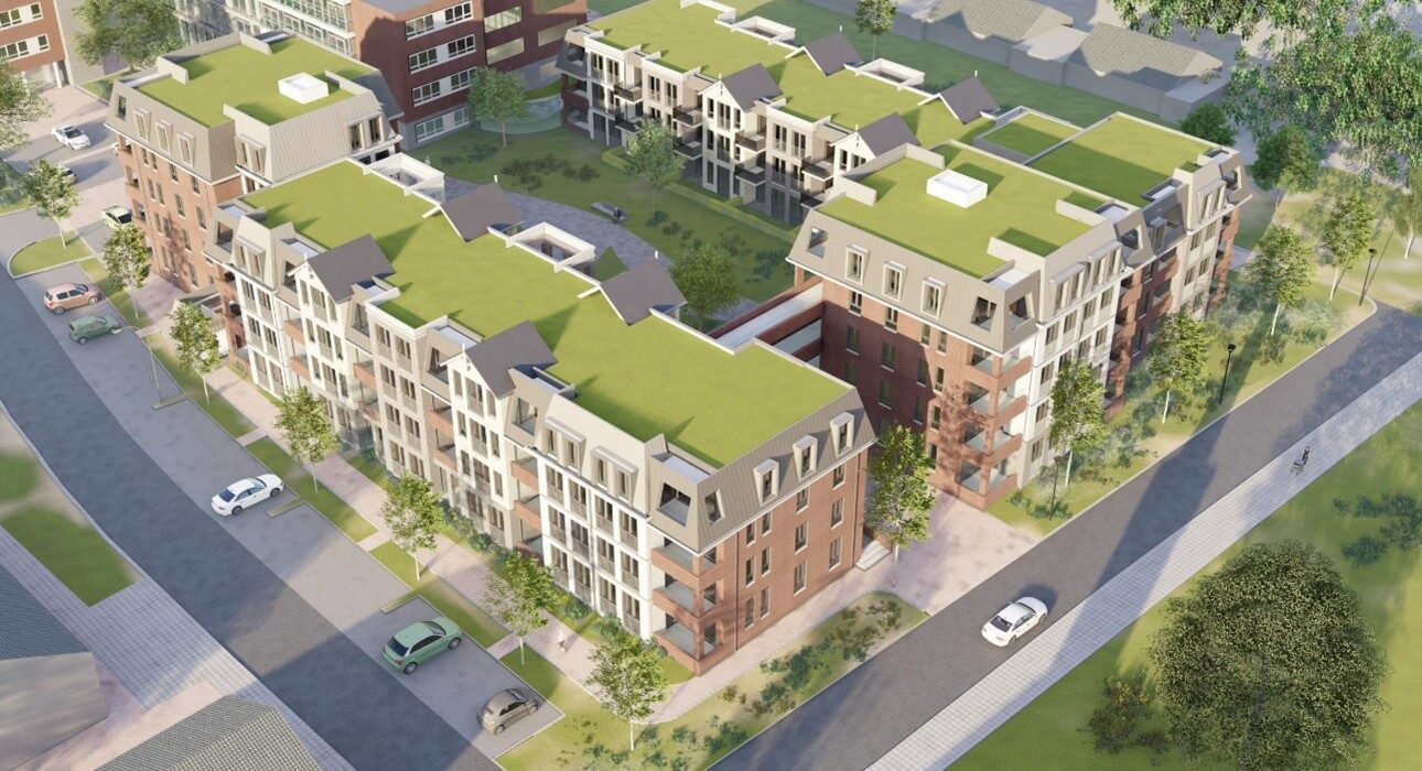 Luchtfoto van een modern appartementencomplex met groene daken, omgeven door wegen en groenvoorzieningen in een stedelijke omgeving.