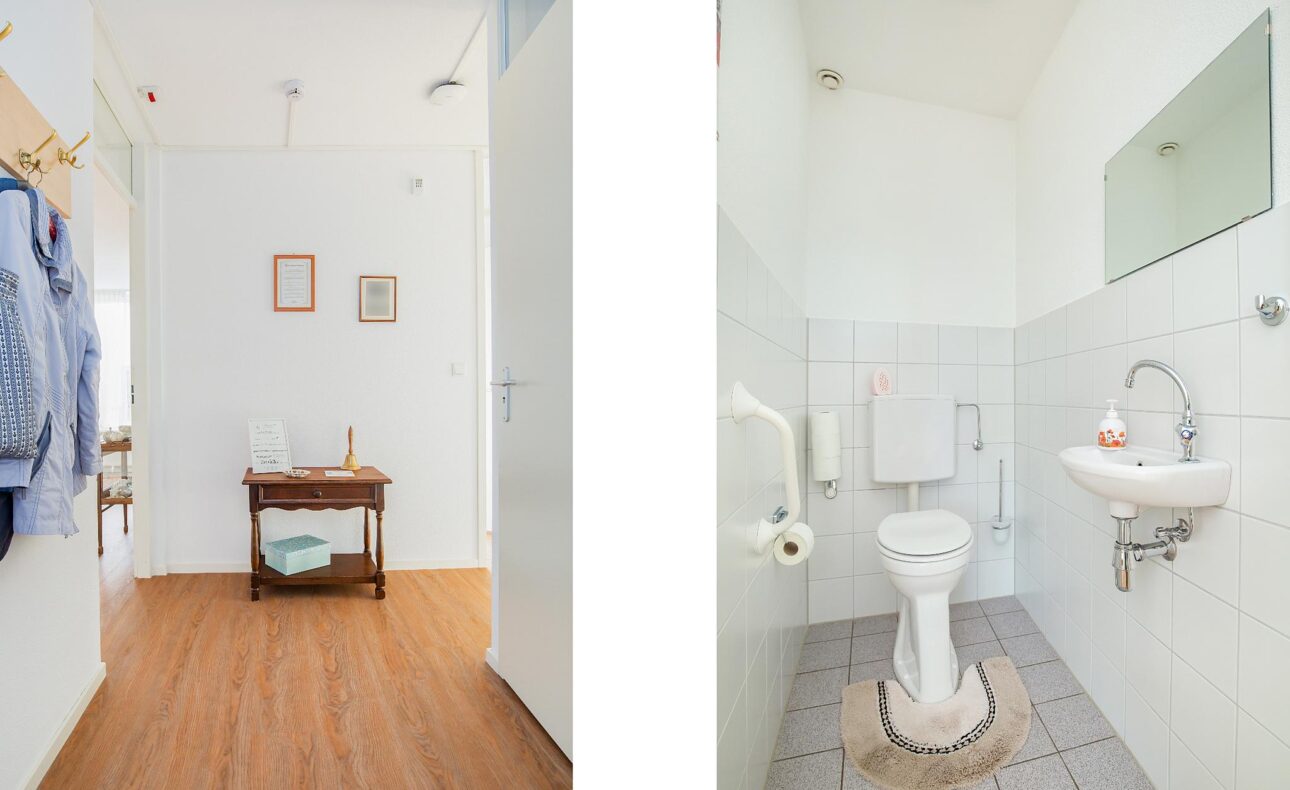 Een lichte gang met houten vloer en een bijzettafel links. Rechts een kleine, witte badkamer met toilet en wastafel.