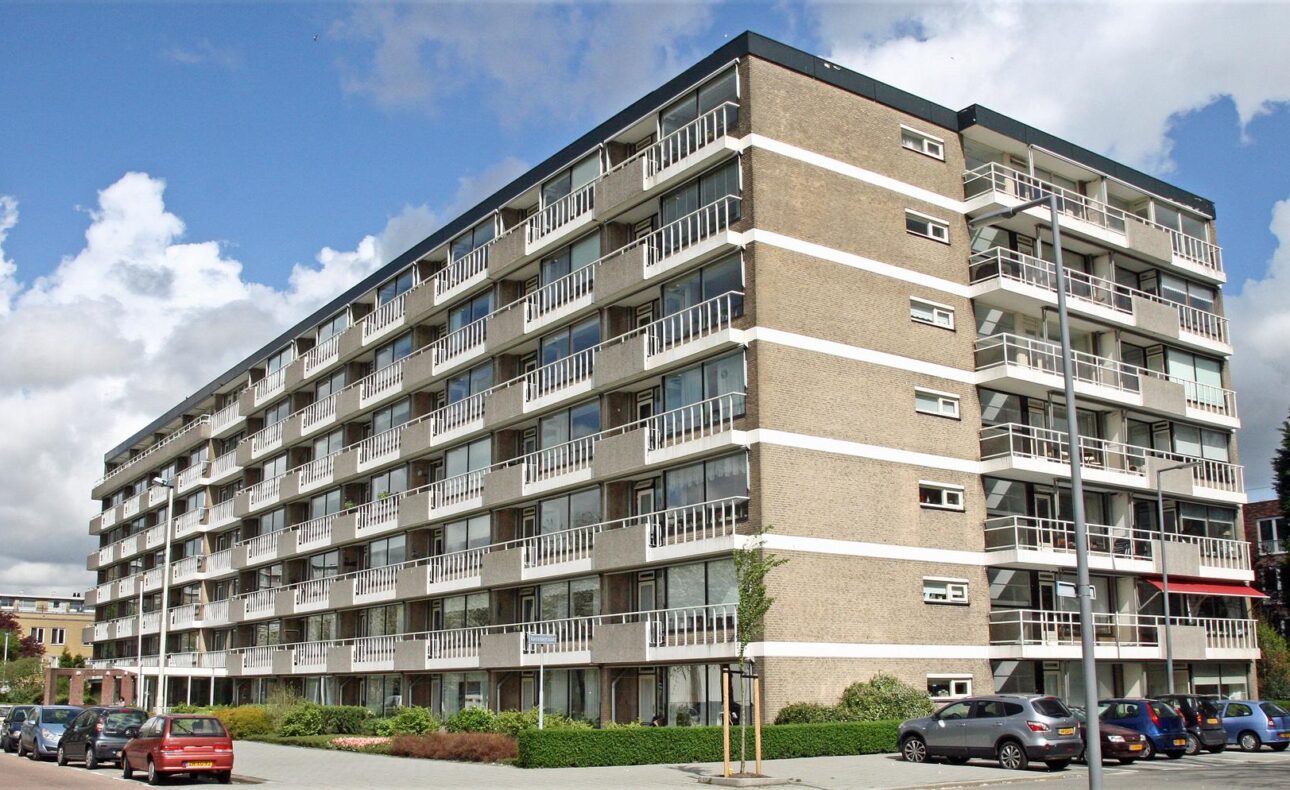 Afbeelding van een groot, modern appartementencomplex met meerdere verdiepingen en balkons, gelegen aan een rustige straat.