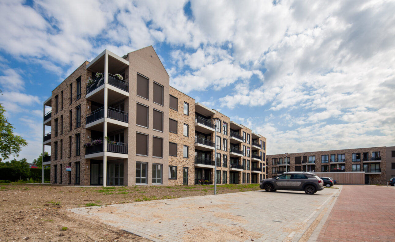 Foto van de gevel van Marnix Staete. De hoek van het gebouw is te zien, met verschillende appartementen en balkons. Voor het complex ligt een ruime parkeerplaats.