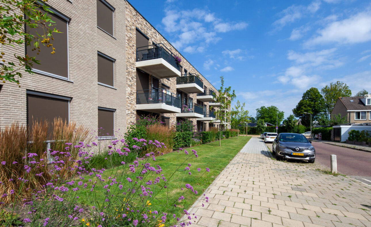 Foto van de gevel van Marnix Staete genomen vanaf het trottoir. Er zijn enkele appartementen en balkons te zien. Voor het gebouw is een mooie tuin met groen en beplanting.
