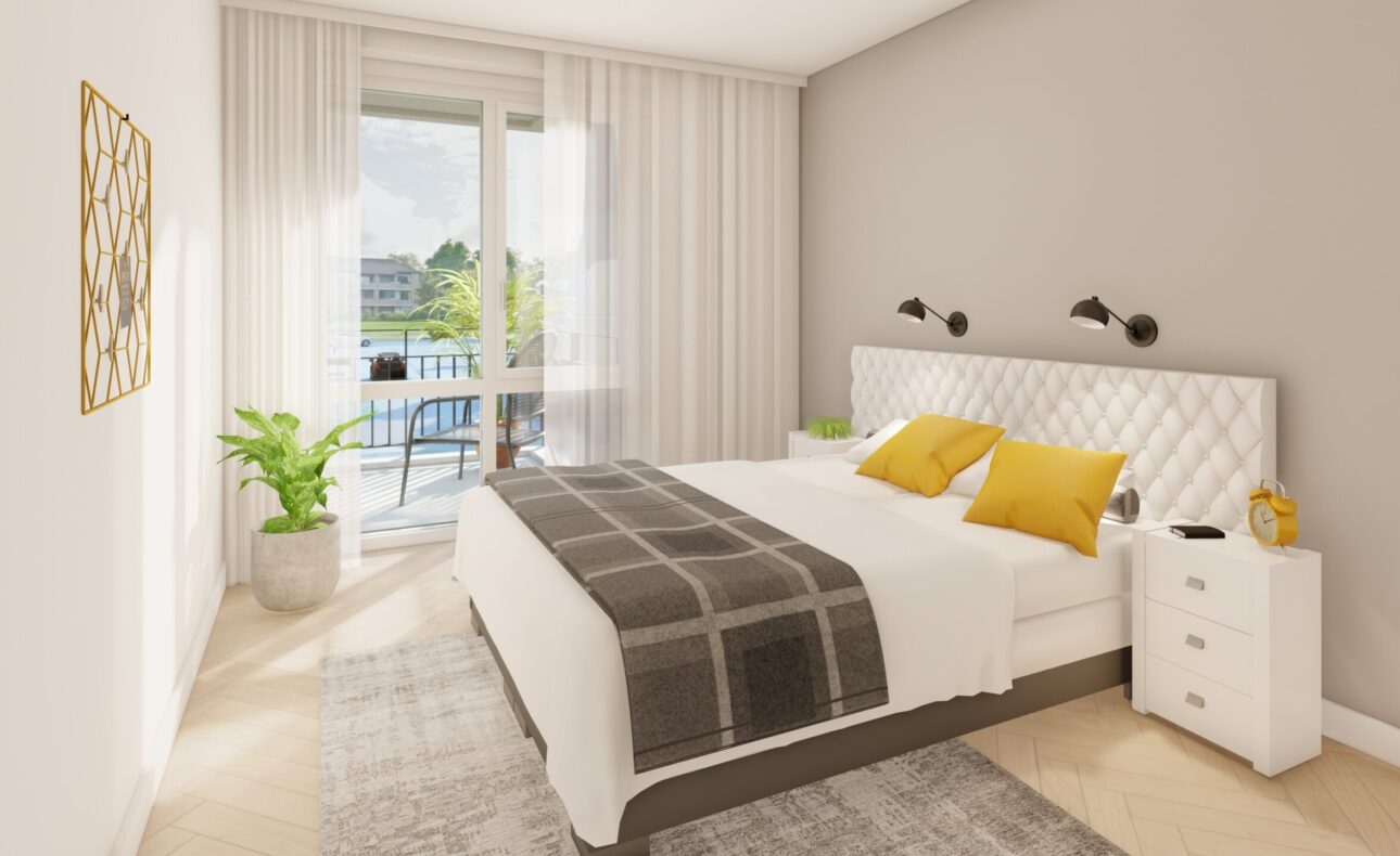 Slaapkamer met een groot bed, witte nachtkastjes, gele kussens en een raam met uitzicht op een balkon en groene omgeving.