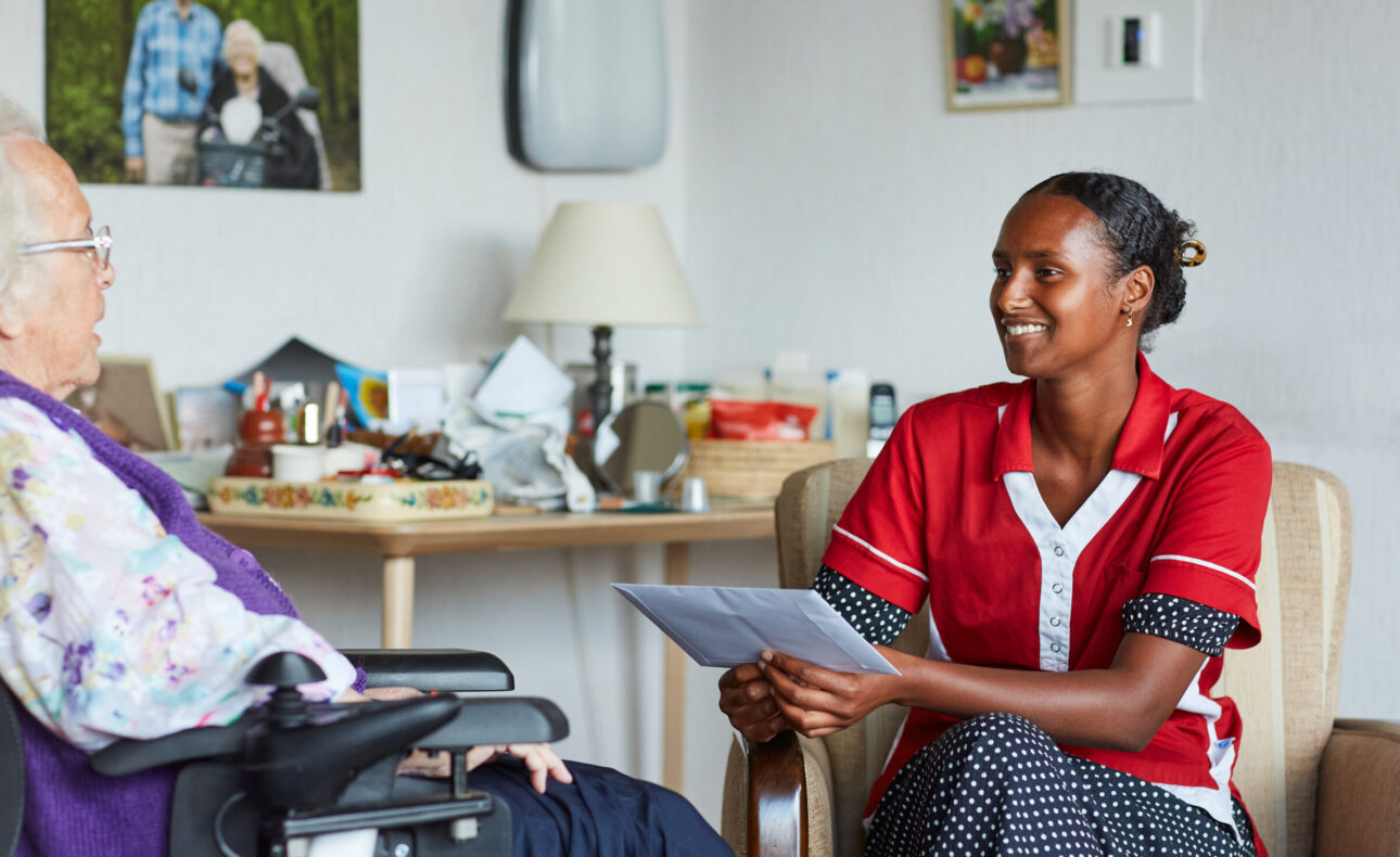 Zorgmedewerker met een bewoner op haar kamer