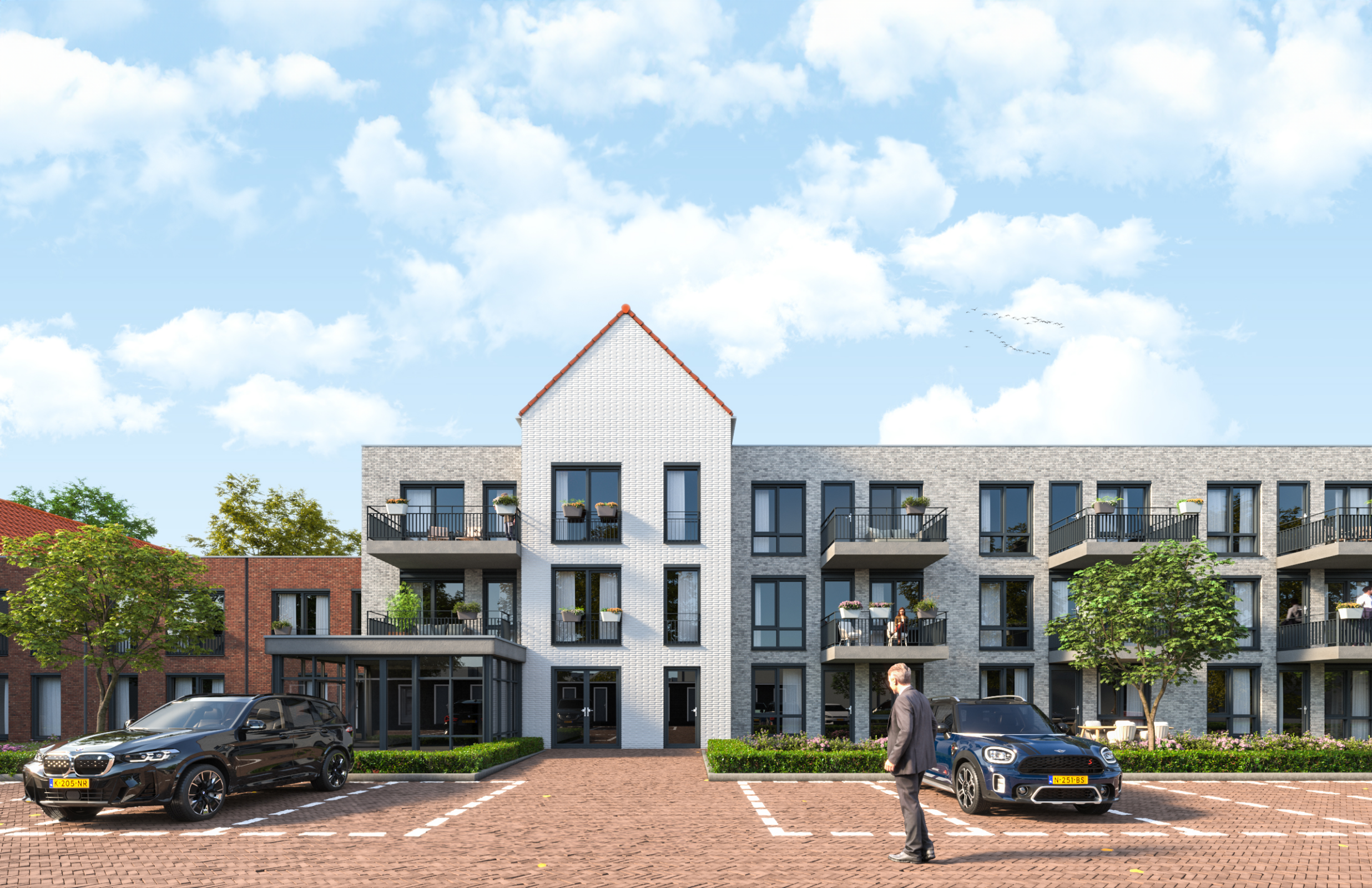Een modern appartementencomplex met drie verdiepingen, omgeven door geparkeerde auto's en bomen, onder een blauwe lucht.