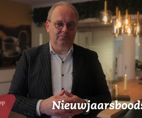 Een man in een keukenachtige omgeving met een kop koffie op de achtergrond. Tekst: "Teunis Stoop" en "Nieuwjaarsboodschap".