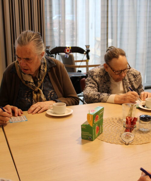 Bewoners rond een tafel doen bingo.