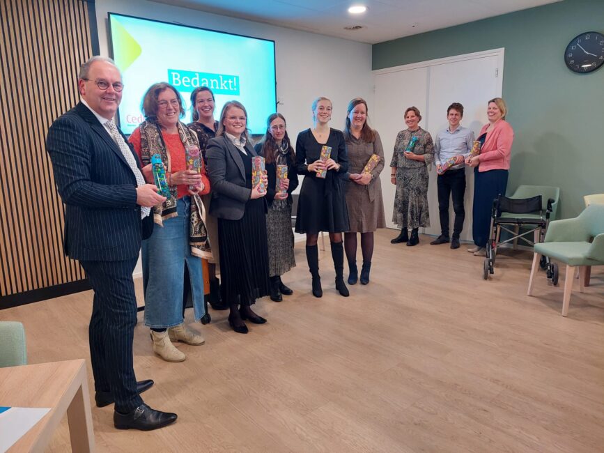 Een aantal mensen op een rij, zij hebben zojuist een cadeautje in ontvangst genomen.
