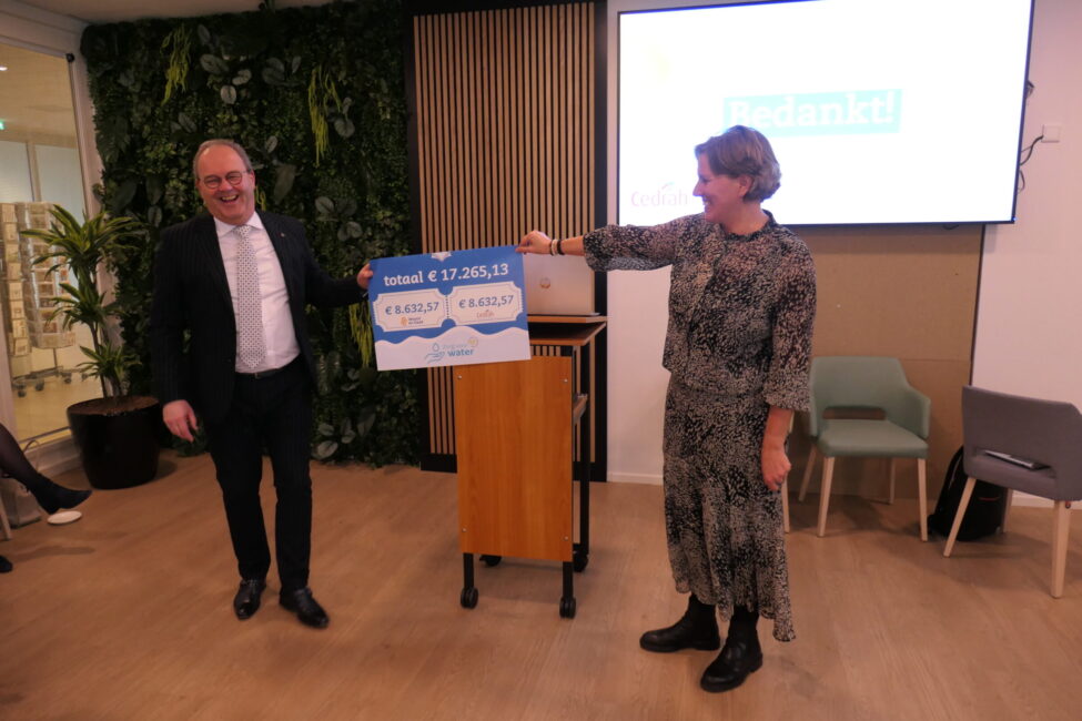 Een man en een vrouw houden samen een groot papier vast met daarop een geldbedrag.