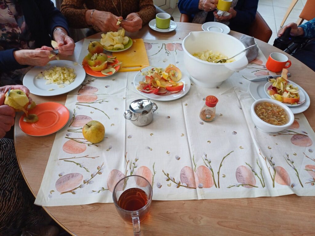 Een tafel met mensen die appels aan het schillen zijn.