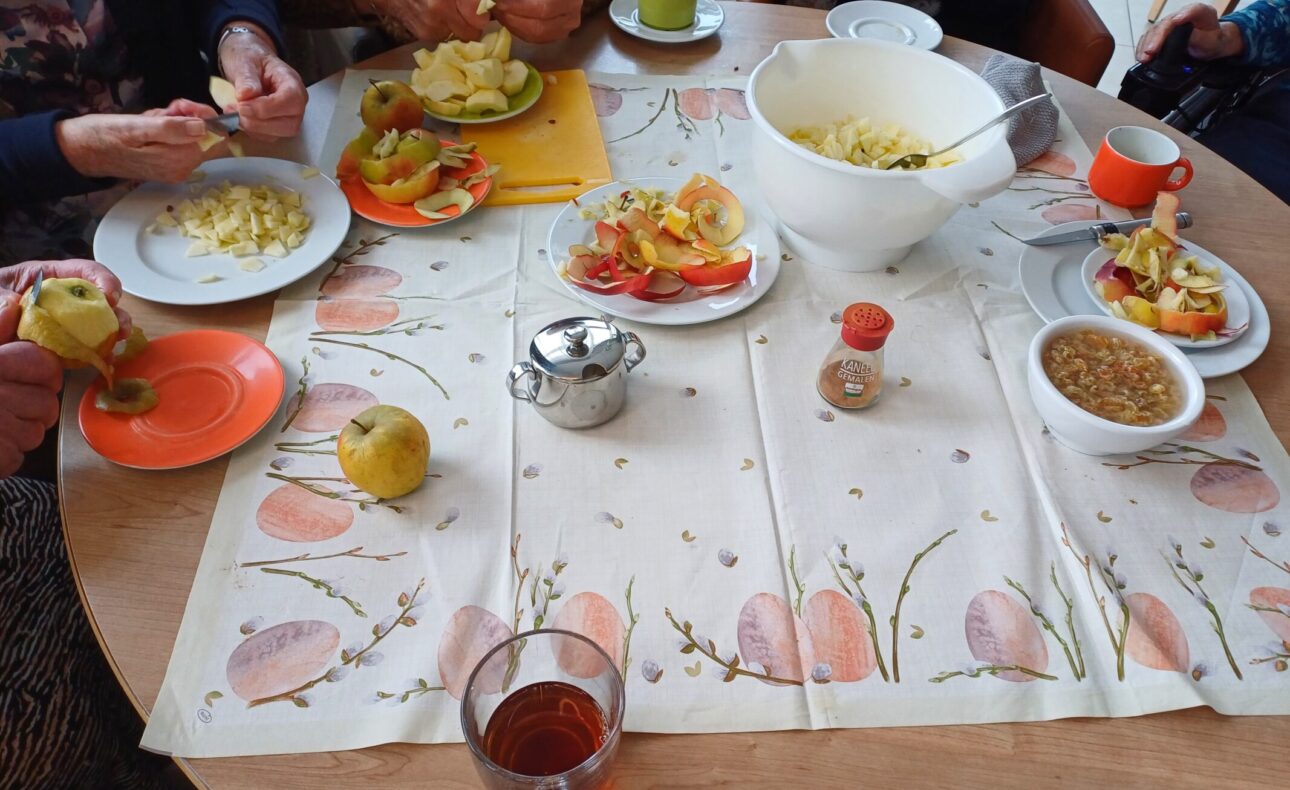 Een tafel met mensen die appels aan het schillen zijn.