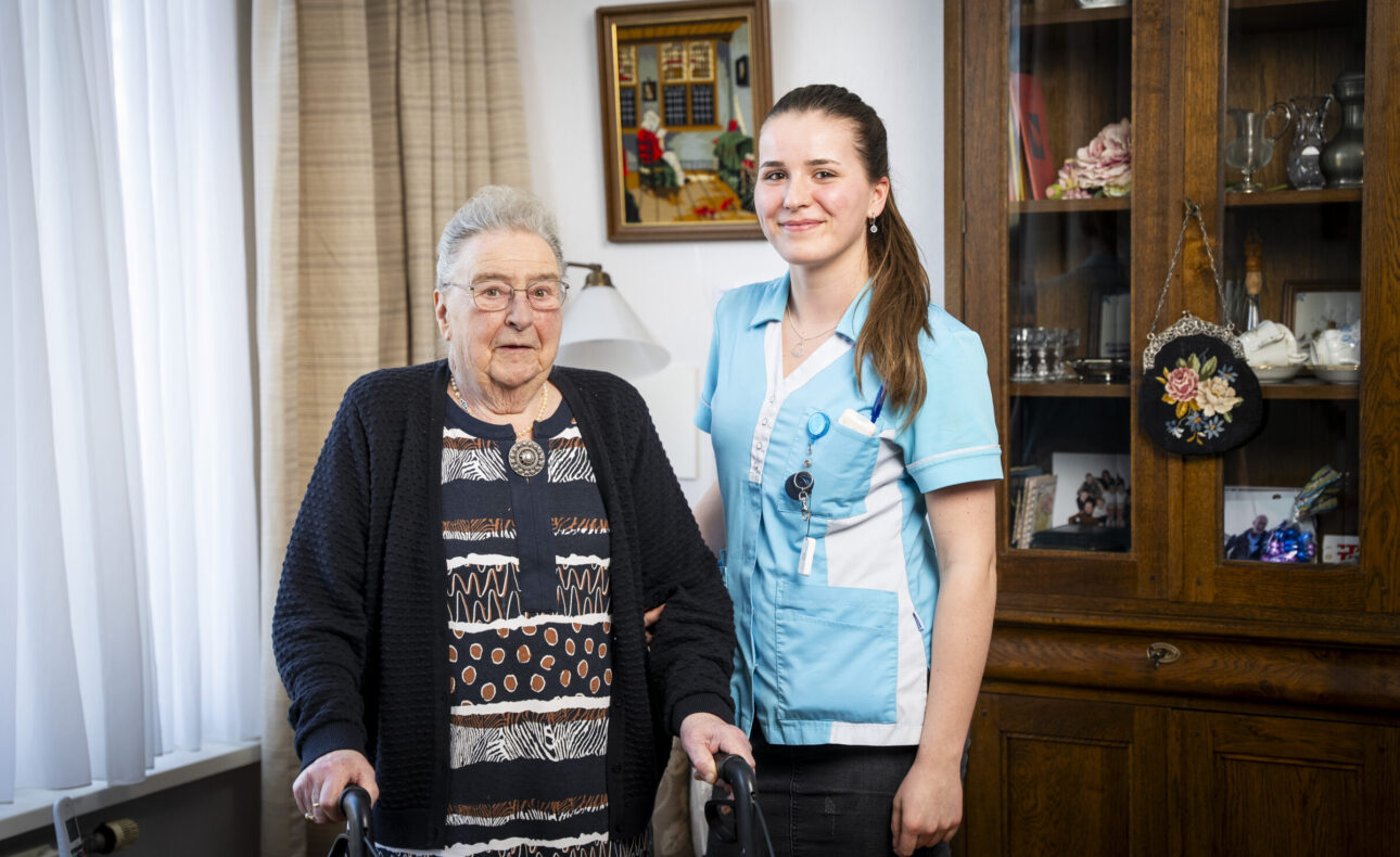 Een zorgmedewerker samen met een cliënt in huiselijke sferen.