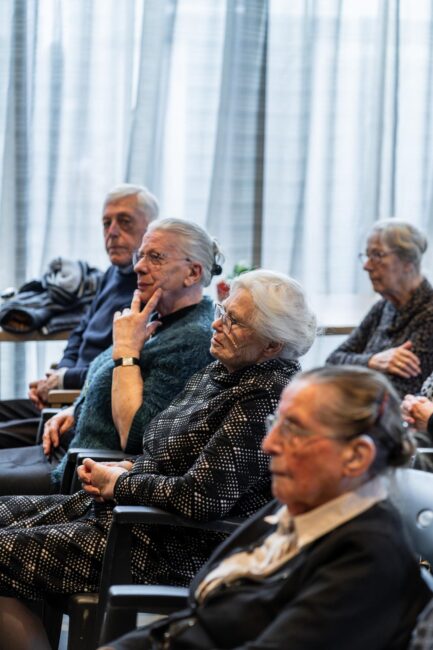 Ouderen zitten te luisteren.