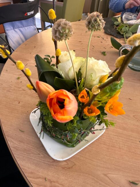 Een bloemstukje met gele en oranje bloemen.