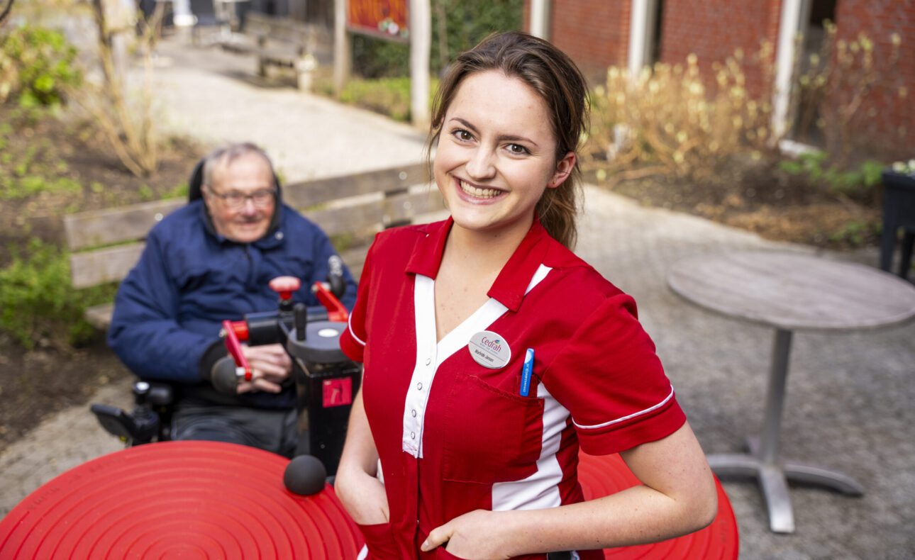 Zorgmedewerker met een bewoner op de achtergrond