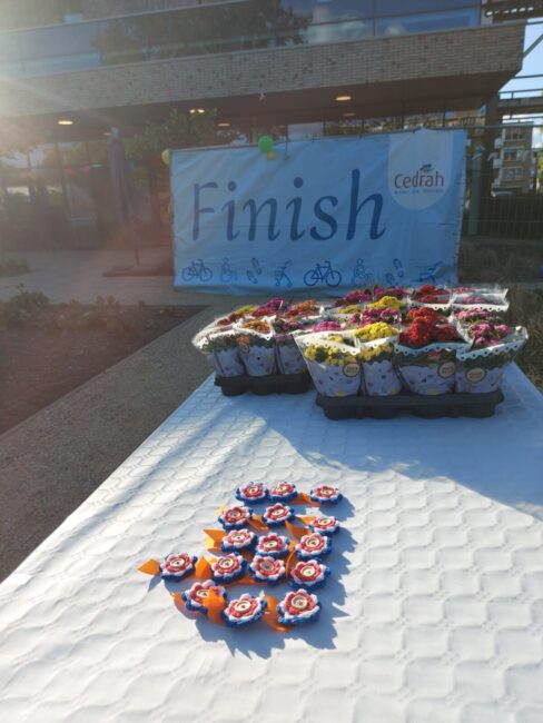 Een tafel met medailles en bloeiende plantjes. Op de achtergrond een spandoek met 'finish' en het logo van Cedrah