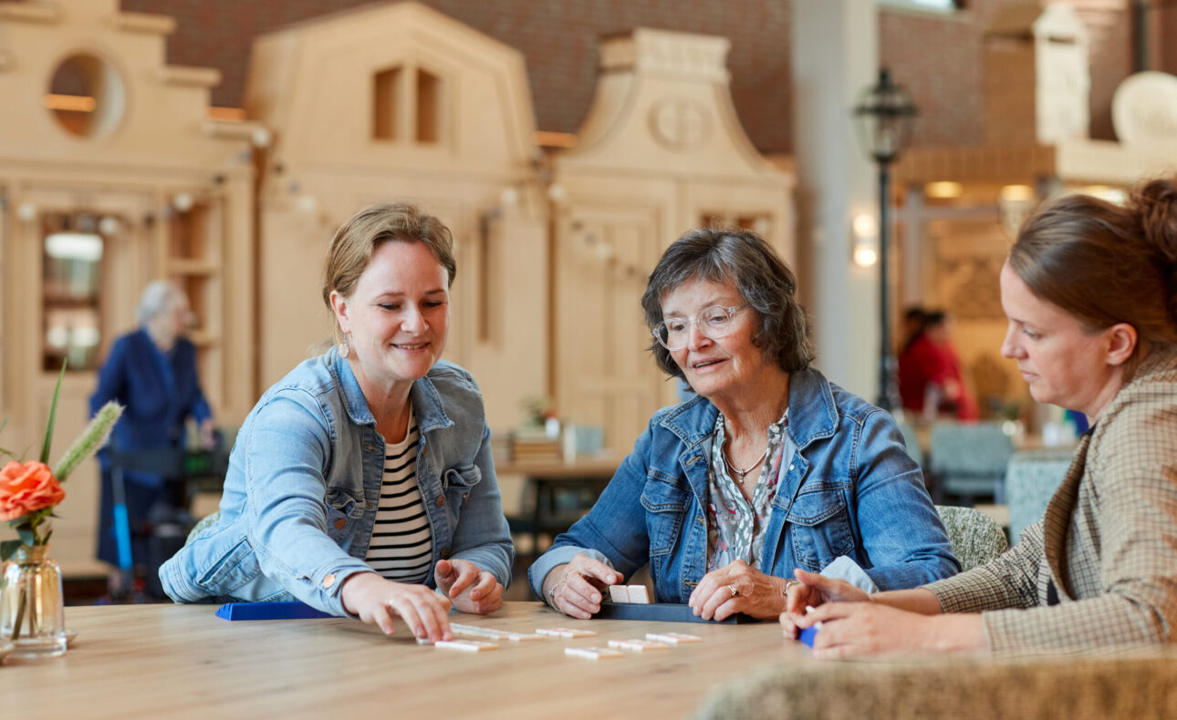 Drie vrouwen die gezellig met elkaar een spelletje spelen.