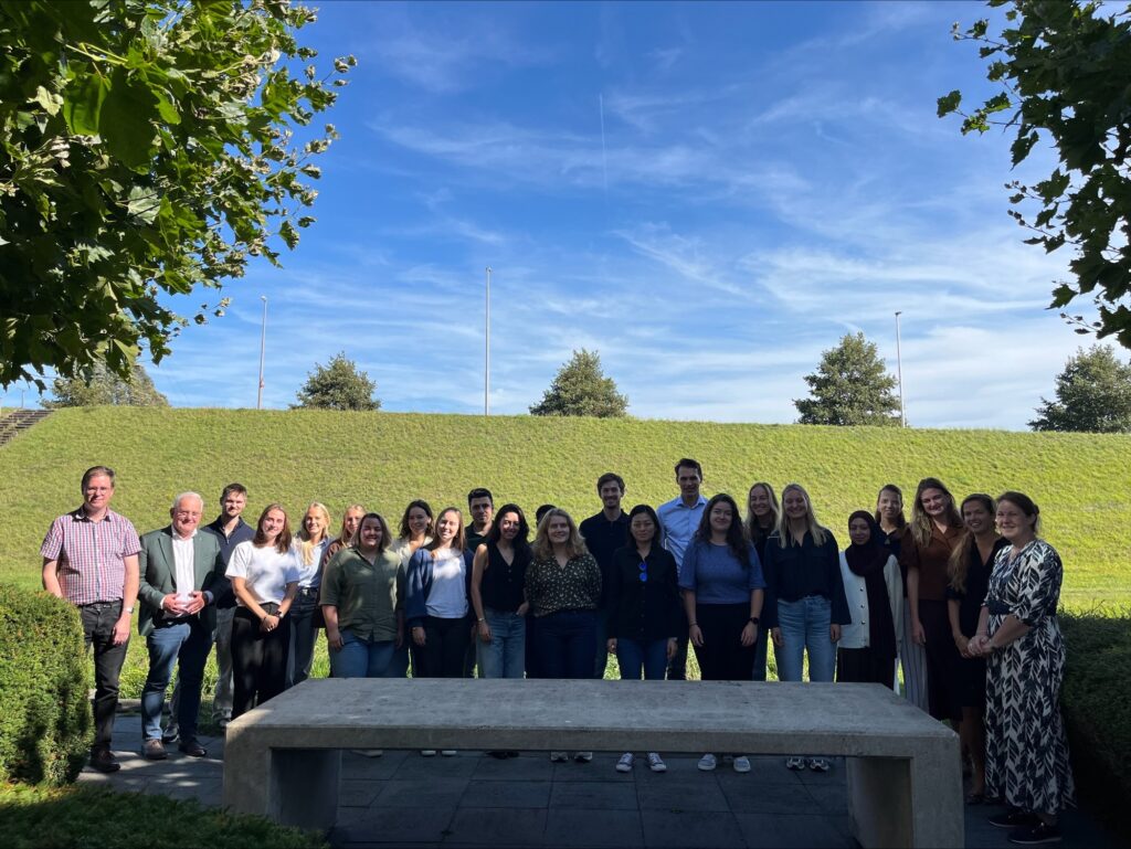 Groep jonge mensen buiten poseert voor de foto.