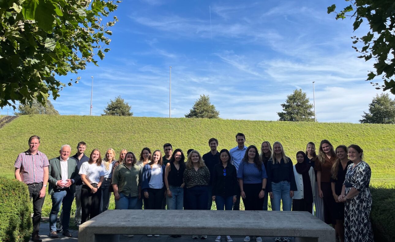 Groep jonge mensen buiten poseert voor de foto.
