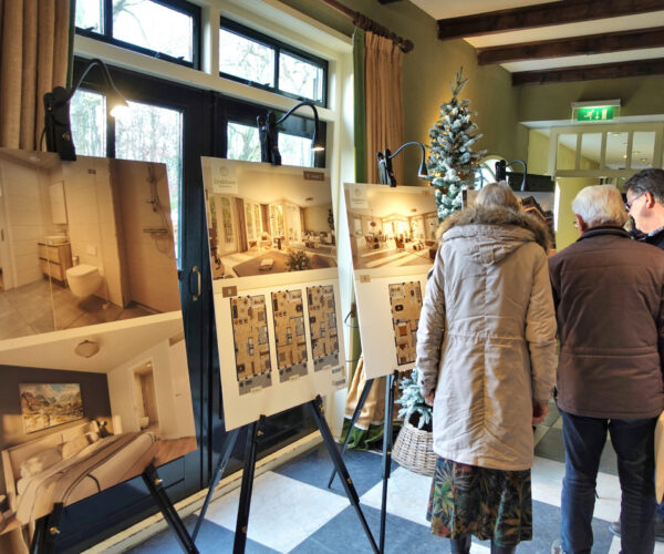 Bezoekers bekijken de plattegronden op schildersezels