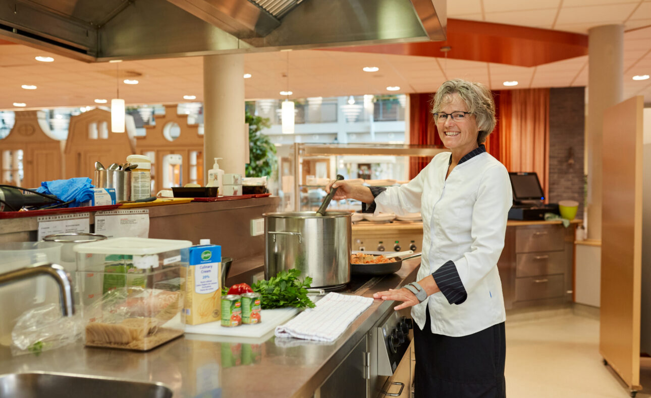 Een medewerker voedingdienst is aan het koken.