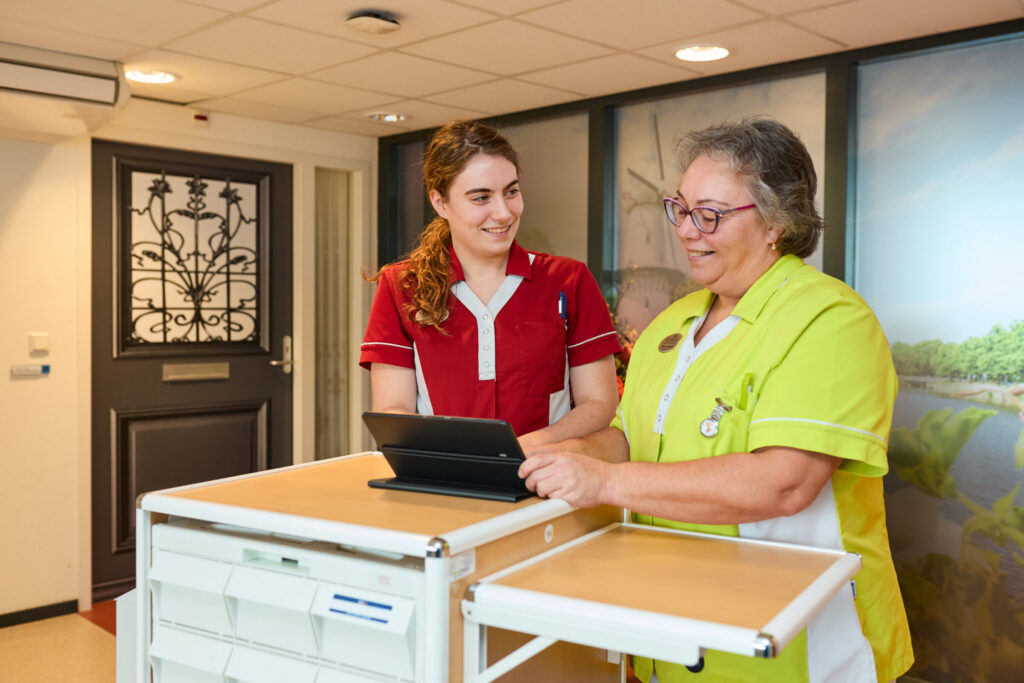 Twee zorgmedewerkers van Cedrah bij een medicijnkar