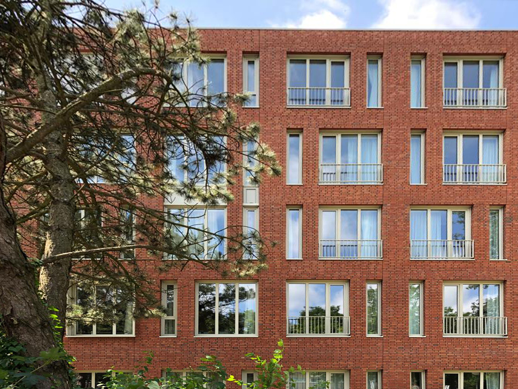 Een nieuw gebouw met op de voorgrond een bloeiende boom.