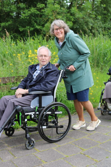 Een vrouw duwt een oudere man in een rolstoel