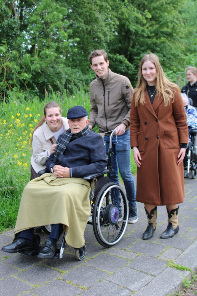 Jongeren duwen een oudere man in een rolstoel