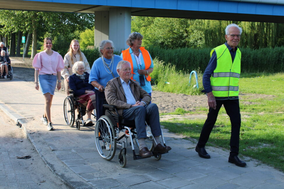 Mensen met ouderen in rolstoelen lopen op een stoep