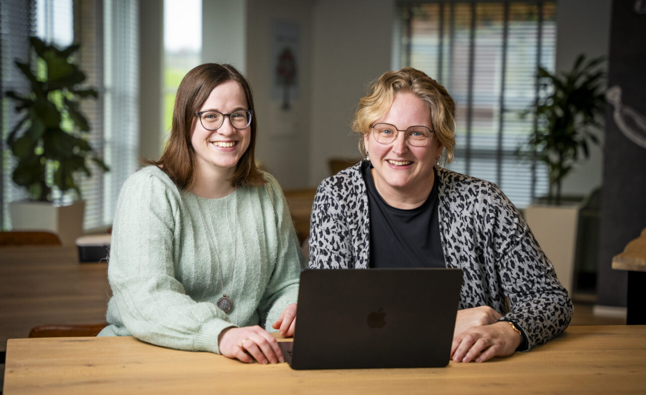 Twee medewerkers werken achter een laptop.