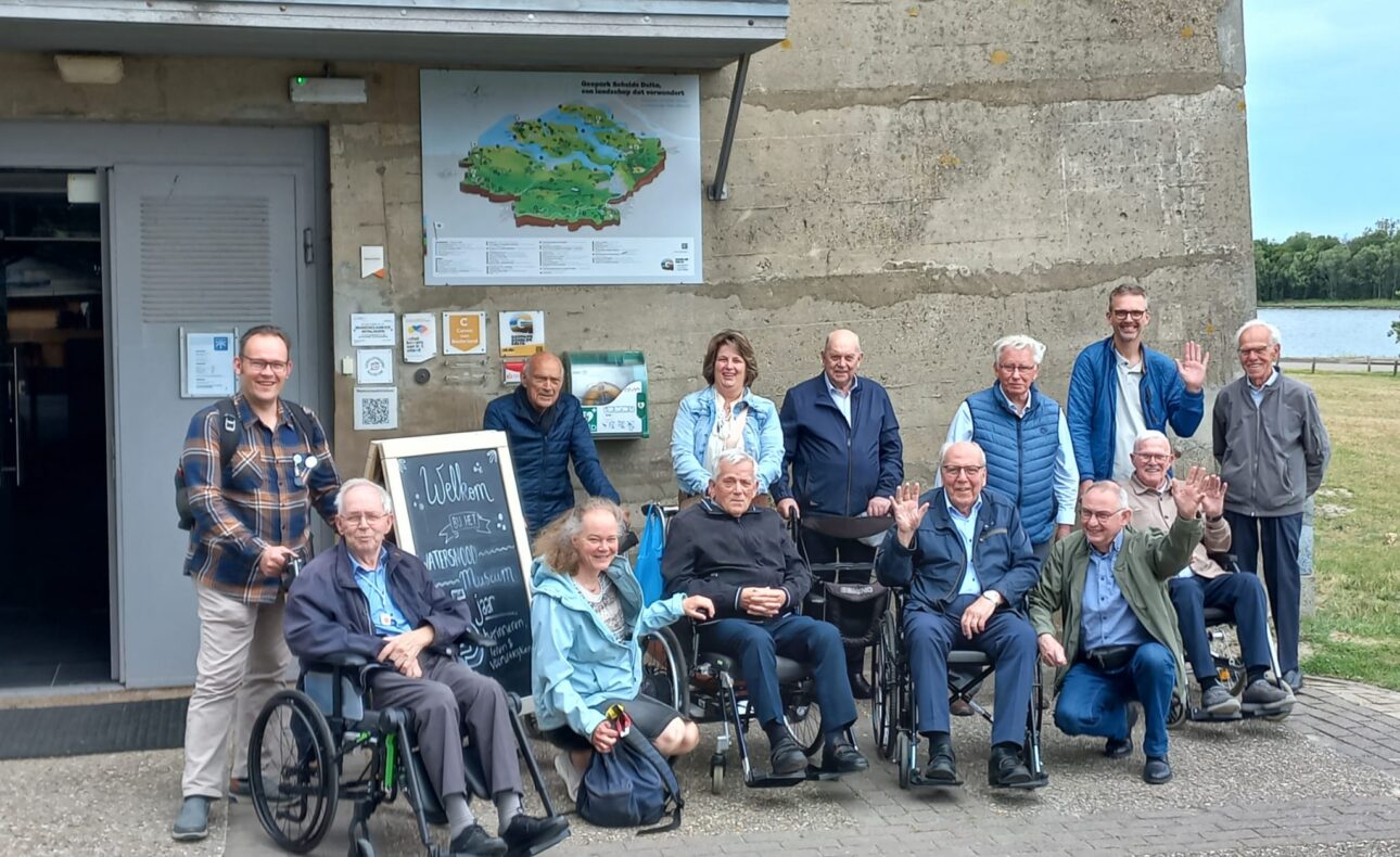 Groep oudere mensen en begeleiders poseren voor de foto