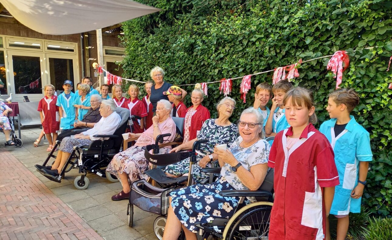 Kinderen in uniformjasjes en ouderen samen op de foto