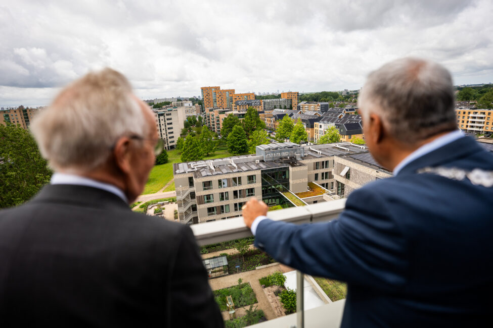 Burgemeester en bewoner kijken uit vanaf balkon