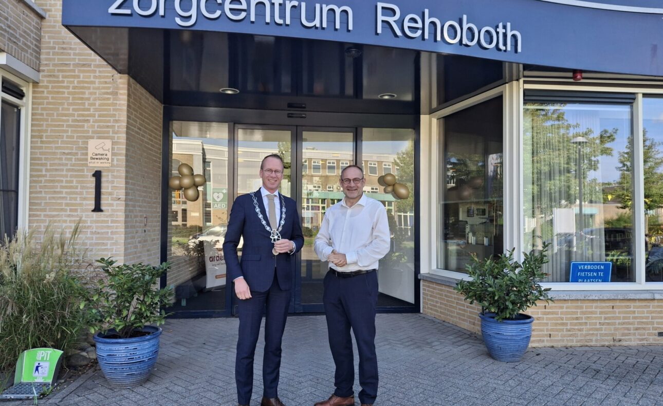 Twee heren, waaronder een burgemeester, voor de ingang van zorgcentrum Rehoboth