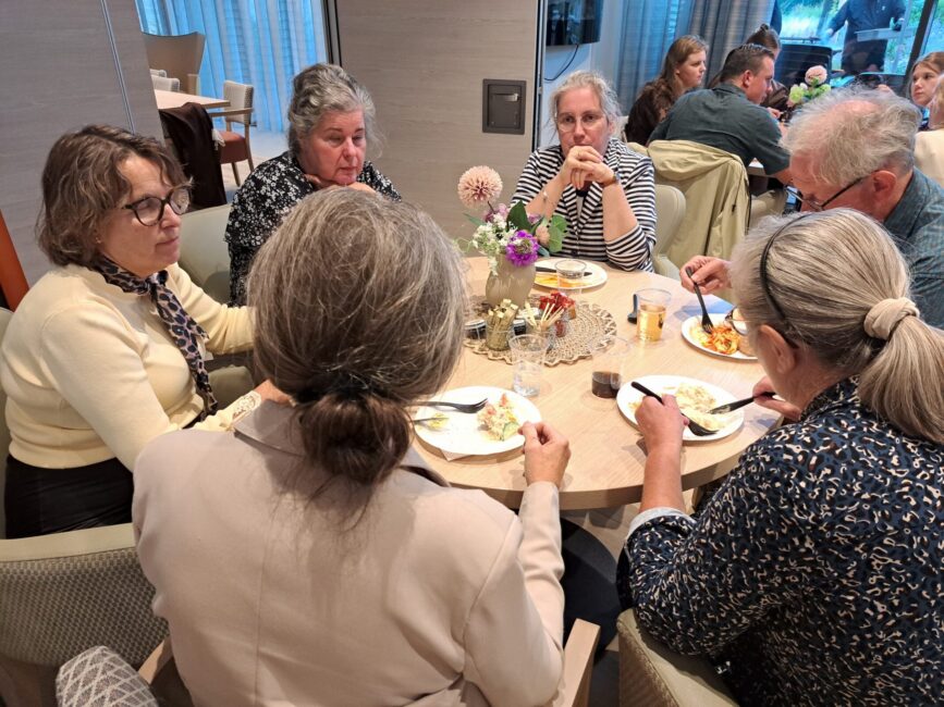 Mensen zitten aan een tafel met elkaar te eten