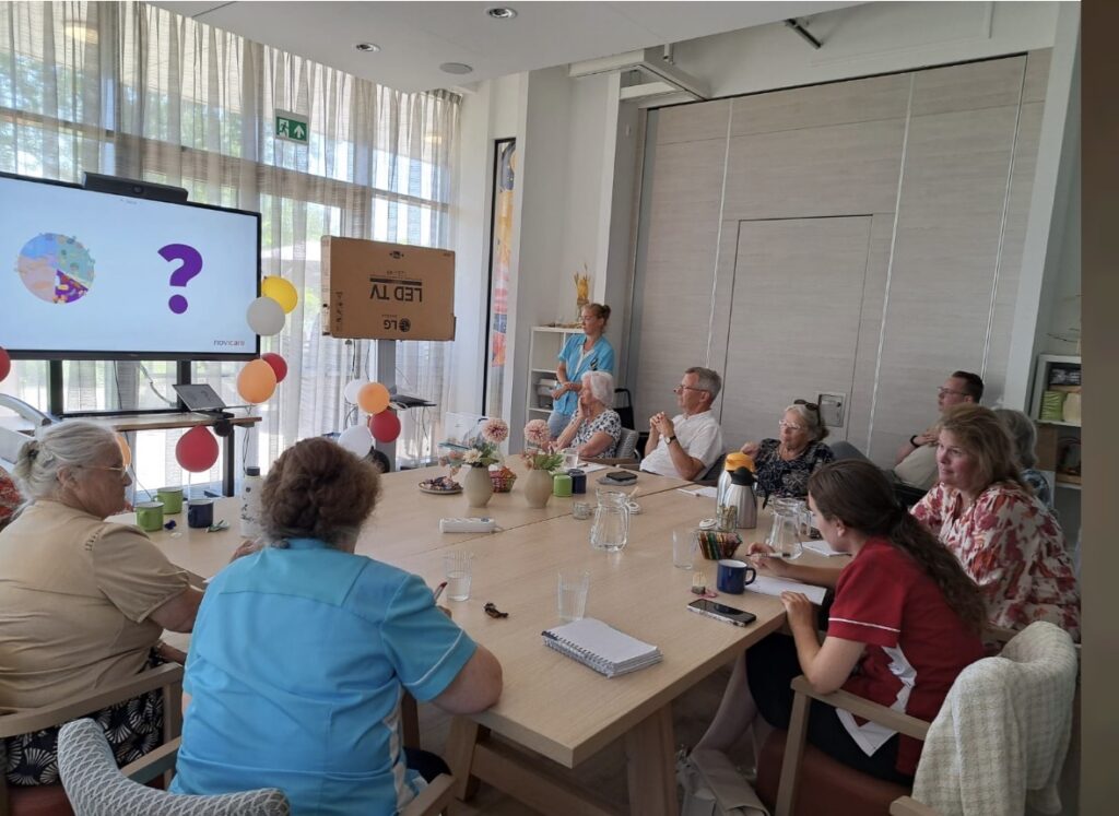 Mensen rond een tafel kijken naar een presentatie