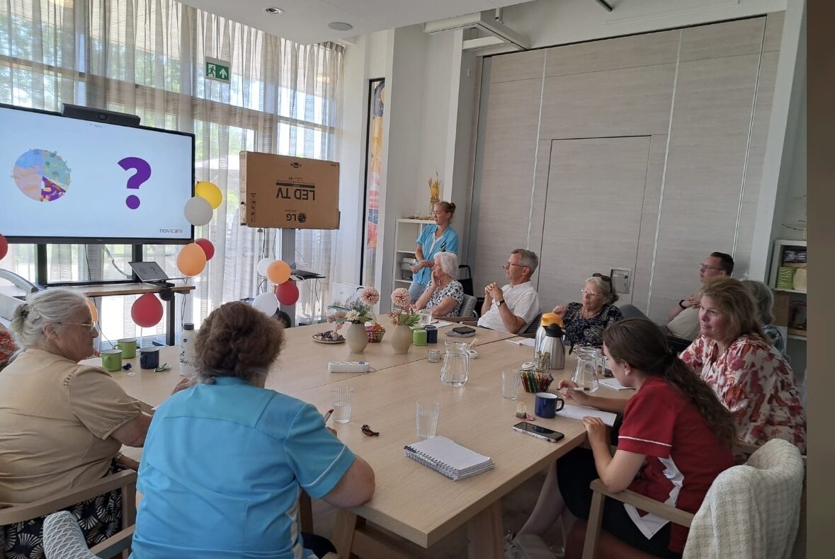 Mensen rond een tafel kijken naar een presentatie